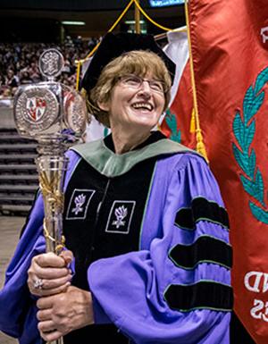 Photo of Domenica Desiderioscioli, clad in Commencement gown and holding scepter.