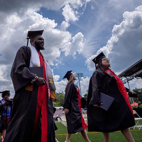 graduates walking on campus in caps and gowns