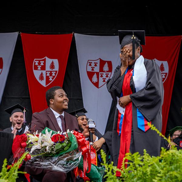 Man proposing to woman in cap and gown on stage
