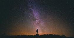 A person standing against the night sky with a ton of stars.