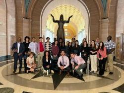 在新泽西州联邦法院的圆形大厅里，学生们站在雕像前合影