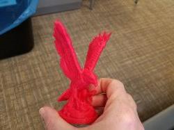手里拿着一个3d打印的小红鹰雕像