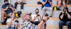 Male faculty in hat wearing facemask teaching class about cameras