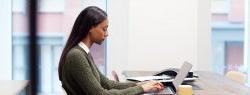African American woman Working On Laptop At Desk In Meeting Room