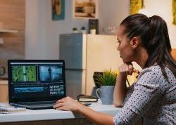 female videographer editing from home on professional laptop