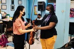 衔接课程协调员将小提琴送给衔接课程的学生
