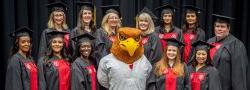 Nursing students posing with Rocky the Red Hawk at the School of Nursing Convocation.