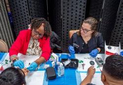 School of Nursing alumni and professor taking a fingerstick sample during a health screening.