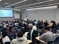 photo of full lecture hall with speaker standing at front