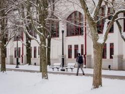 大雪中，学生们走在学生中心广场旁的小路上.
