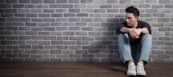 一个人靠在砖墙上坐着