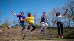 四名学生穿着不同的t恤，代表他们的学院或学院在大学圆形剧场跳跃