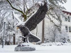 Large MSU Red Hawk bronze statue covered in snow.